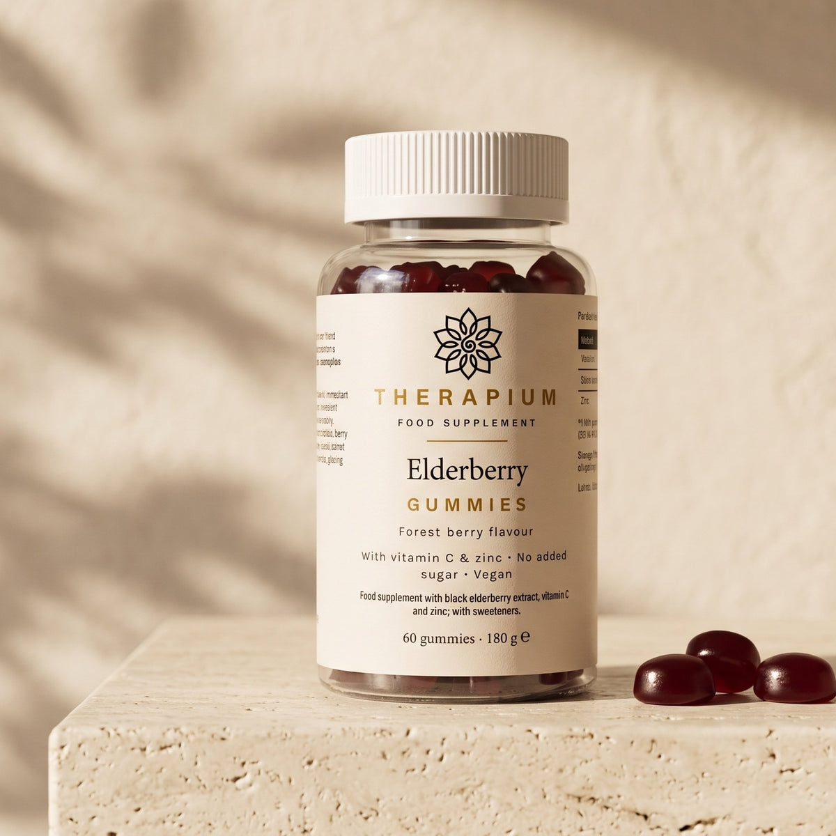 Therapium Elderberry Gummies, the jar on a travertine ledge in morning light with three burgundy gummies beside it