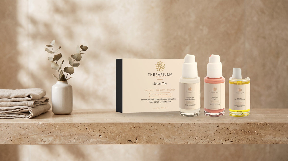 Therapium Serum Trio box with COLLAVIS, RENOVÉA and BAKURIS serums on a travertine bathroom shelf in morning light