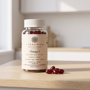 Therapium Omega 3 Gummies Kids jar on a kitchen counter beside loose raspberry gummies