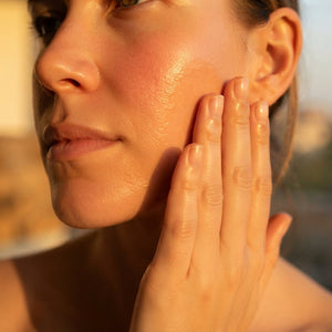 Therapium Nourishing Facial Oil being applied to the cheek in warm light