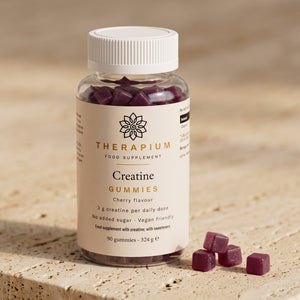 Therapium Creatine Gummies jar on travertine stone, cherry-red gummies beside it