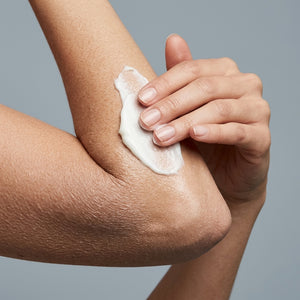 White cream being smoothed onto a dry elbow with Therapium UREVA™ Rough Skin Body Cream